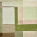 Detail of a handknotted rug in a graphic geometric design in layered shades of a green, taupe and warm pink.