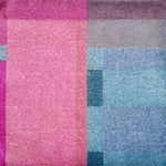 Detail of a handknotted rug in a graphic geometric design in layered shades of a fuchsia, magenta and blues.