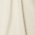 Draped piece of high-pile bouclé fabric in cream.