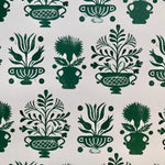 Detail of wallpaper in a repeating vase and plant print in green on a white field.