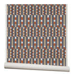 Wallpaper roll with a pattern of vertical stripes of light brown, navy blue and dashes of rust red and white.