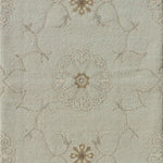 Close up of hand woven rug in a floral filigree pattern in grey, tan and cream on a pastel aqua blue field.