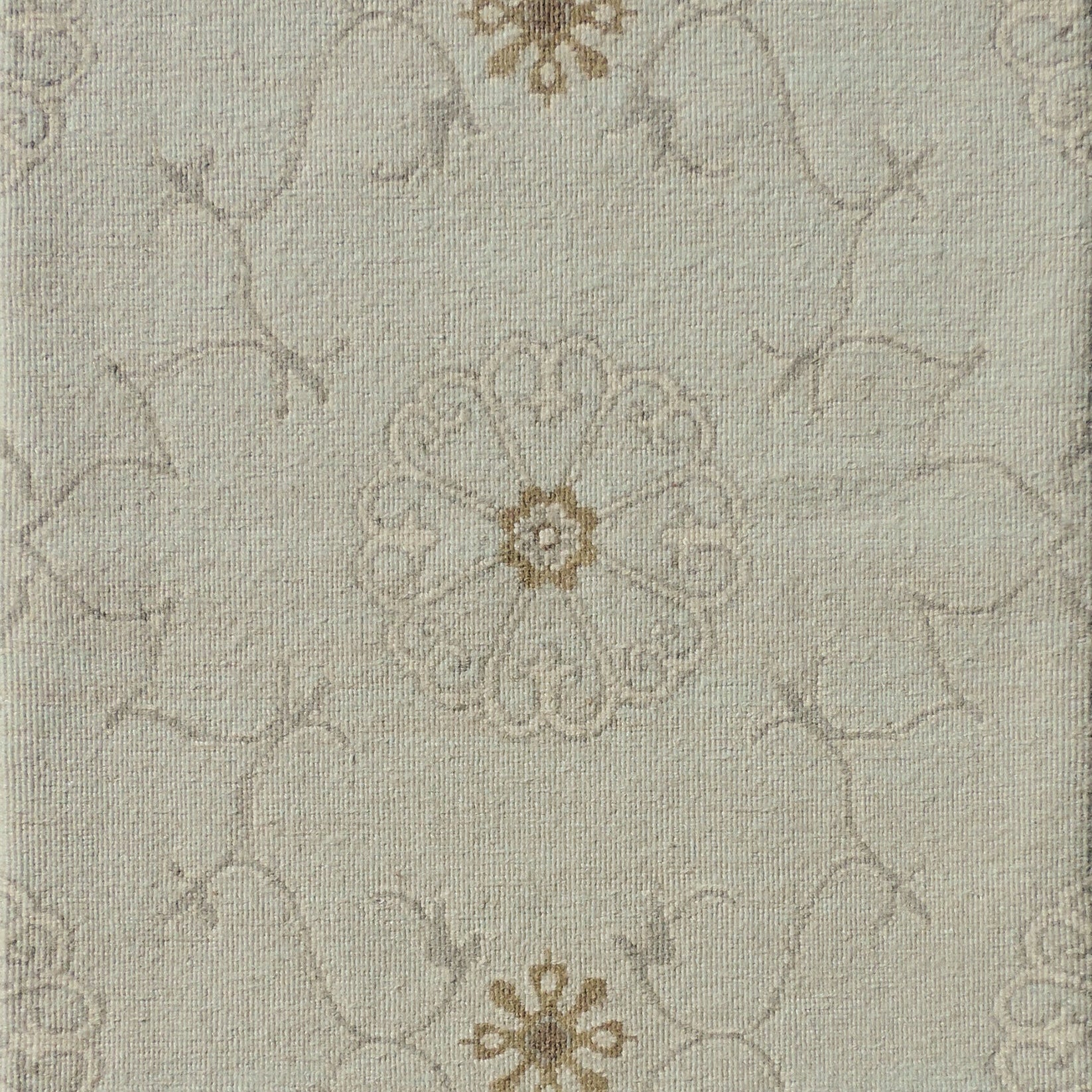 Close up of hand woven rug in a floral filigree pattern in grey, tan and cream on a pastel aqua blue field.