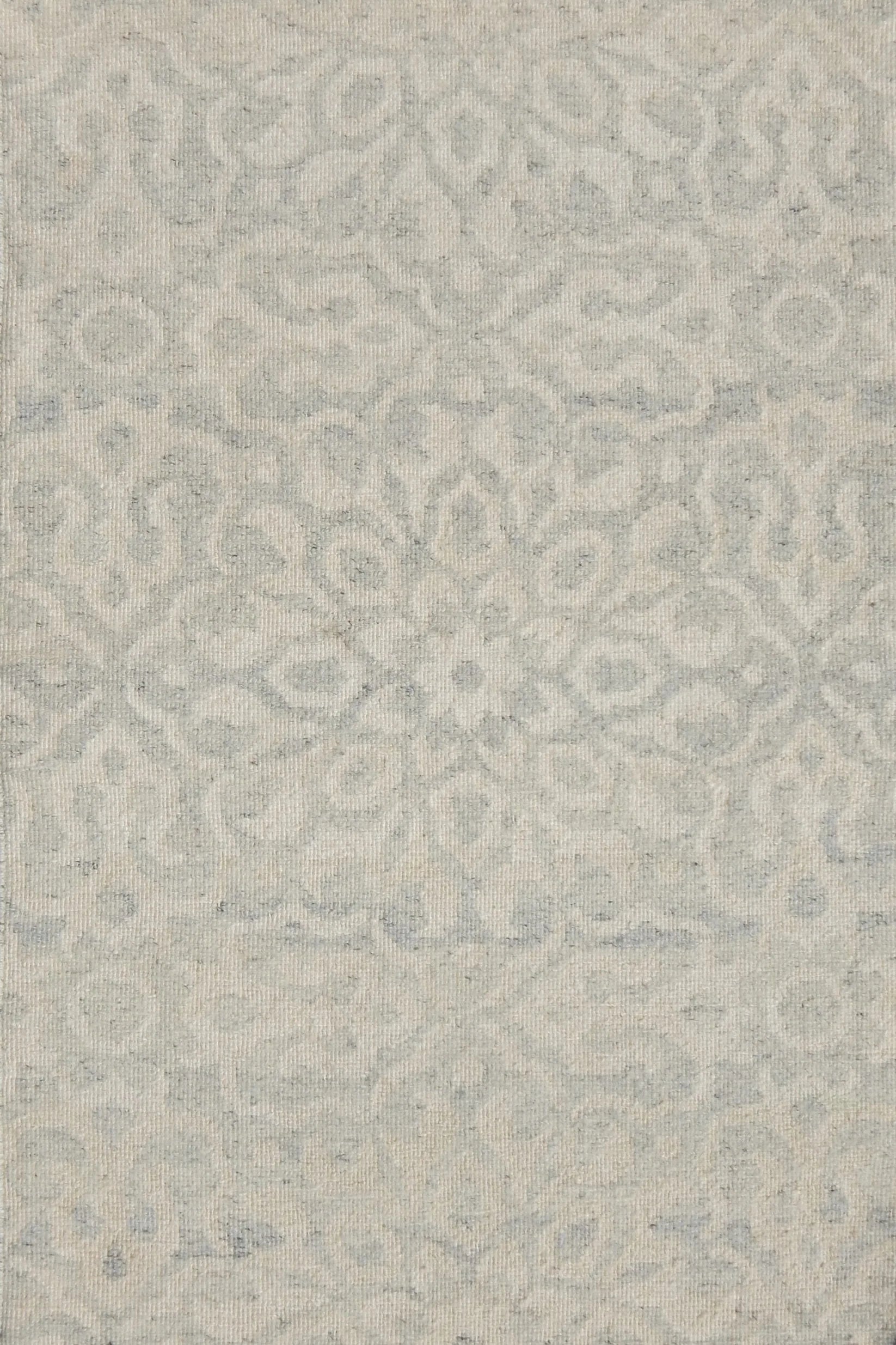Close up of a handwoven rug in an ornate damask medallion design in cream on a grey field. 