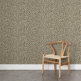 A wooden chair stands in front of a wall papered in a painterly animal print in white and brown on a gray field.