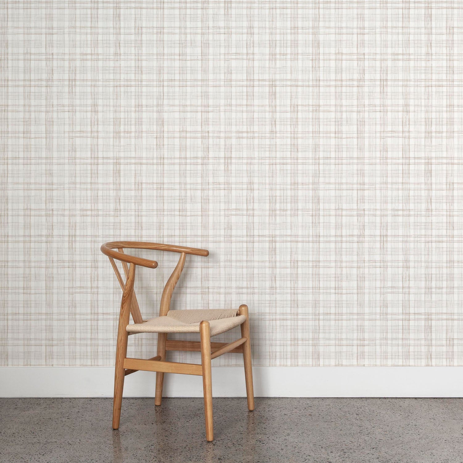 Wooden chair against wallpaper with watercolor plaid pattern in shades of taupe. 