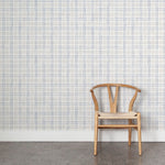 Wooden chair against wallpaper with watercolor plaid pattern in shades of light blue. 