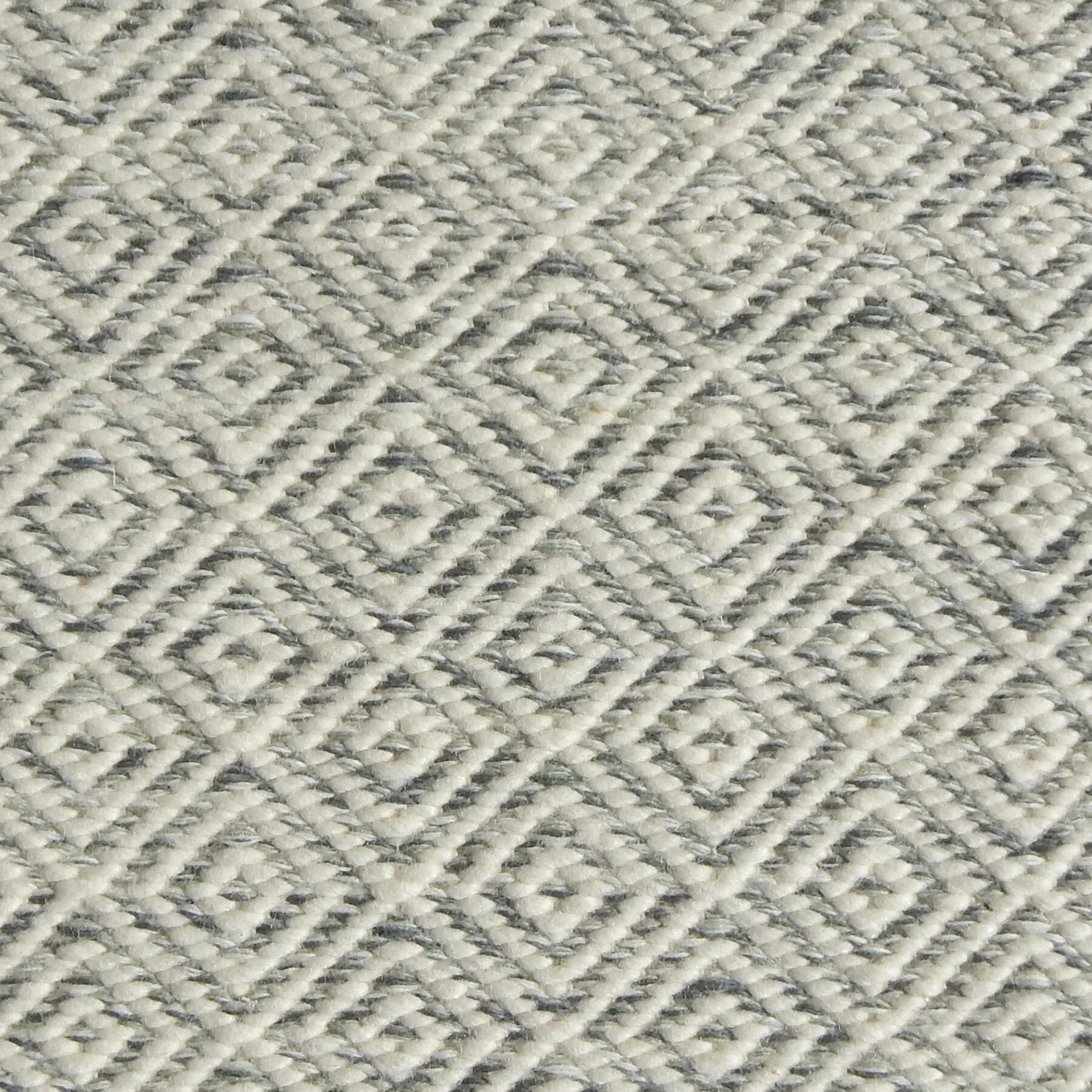 Detail of handwoven rug with diamond pattern in cream and shades of grey-blue.