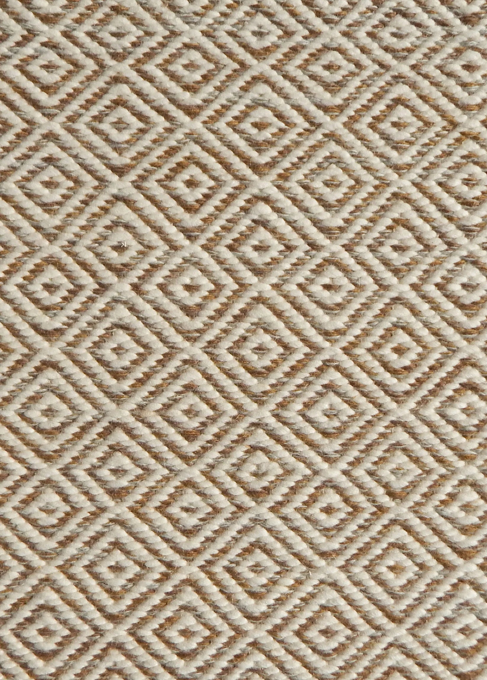 Detail of handwoven rug with diamond pattern in cream and shades of brown. 