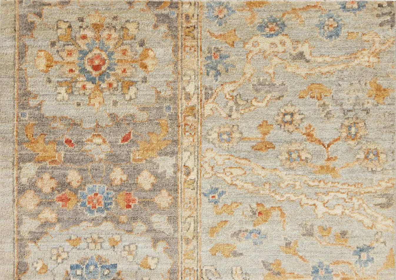 Detail of a Handknotted rug with an ornate Damascus design in blue, grey, and tan. 
