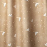 Draped fabric a flying geese and star pattern in white on a warm tan watercolor field. 