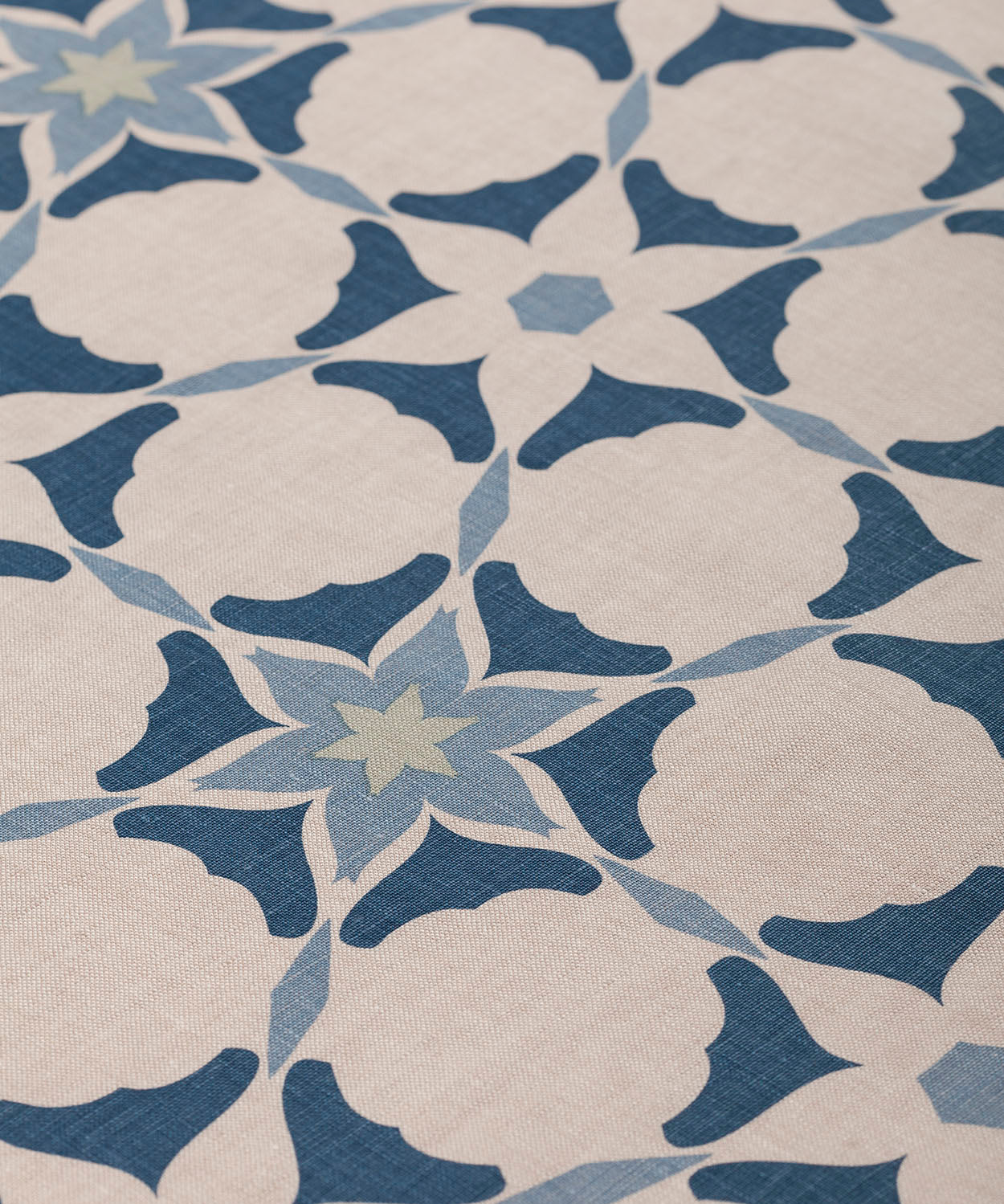 Detail of fabric in a geometric star print in shades of blue and navy on a tan field.