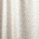 Draped fabric in a painterly branch print in white on an ecru watercolor field.