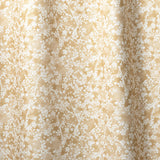Draped fabric in a painterly branch print in white on a warm yellow watercolor field.
