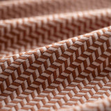 Close-up of brown textured fabric with a herringbone pattern light folded. 