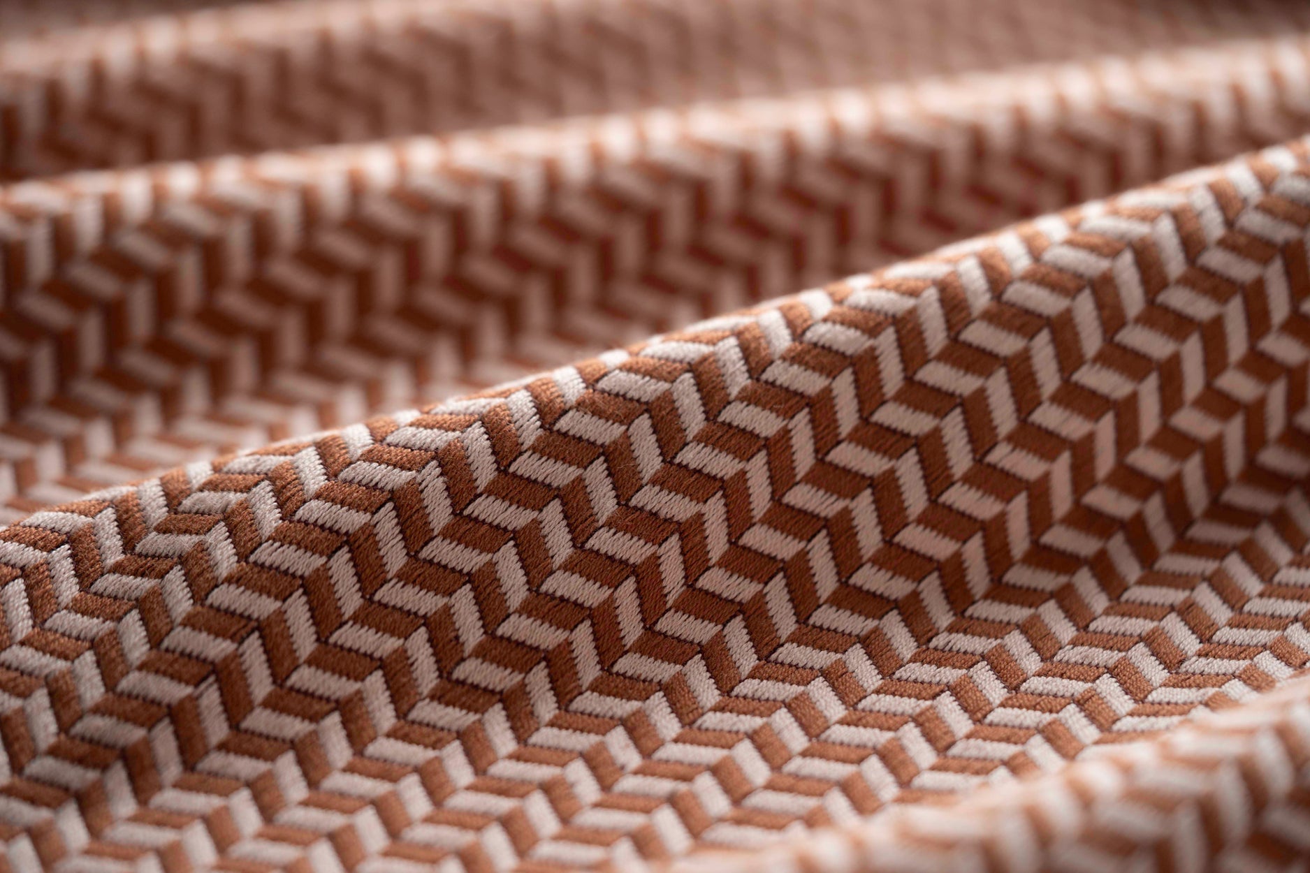 Close-up of brown textured fabric with a herringbone pattern light folded. 