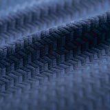 Close-up of a blue textured fabric with a herringbone pattern light folded. 