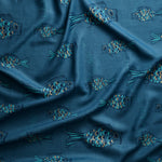 Close up of gently draped printed linen with a pattern of hand-drawn fish in navy with tan and  blue scales and scattered bubble dots on dark blue.