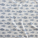 Close up of gently draped woven Indoor-Outdoor fabric with playful fish print in shades of blue on white. 