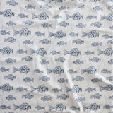 Close up of gently draped woven Indoor-Outdoor fabric with playful fish print in shades of blue on white. 