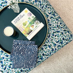 A fabric ottoman upholstered in a playful polka dot print and topped with a tray, candle and book.