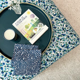 A fabric ottoman upholstered in a playful polka dot print and topped with a tray, candle and book.