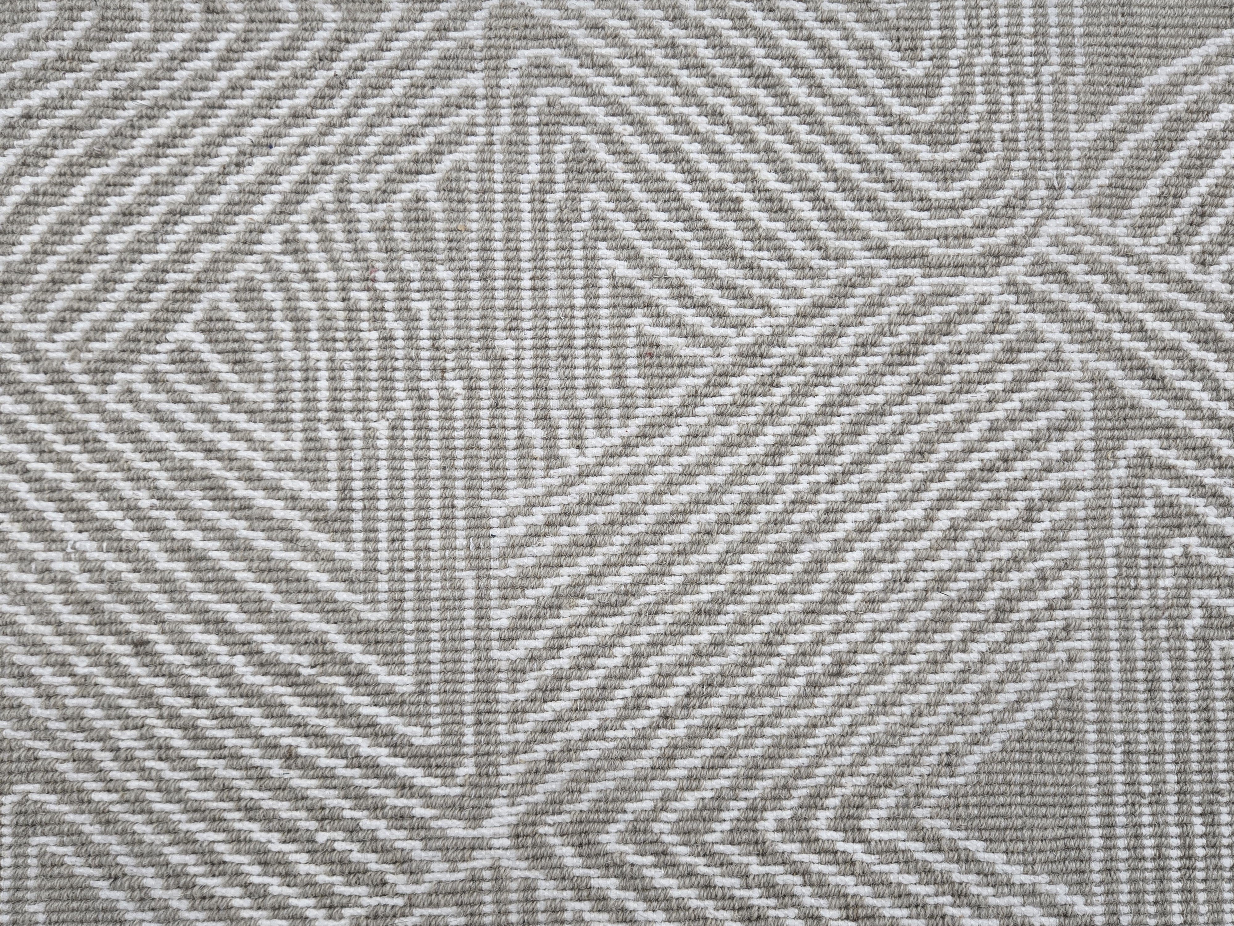 Broadloom carpet sample in a geometric linear pattern in cream on a taupe field. 