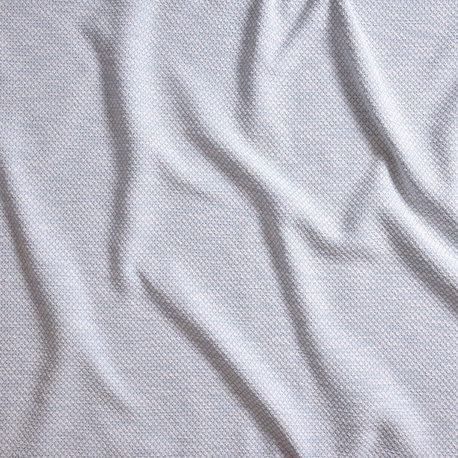 Close up of gently draped woven Indoor-Outdoor fabric with basketweave texture in white and light blue.
