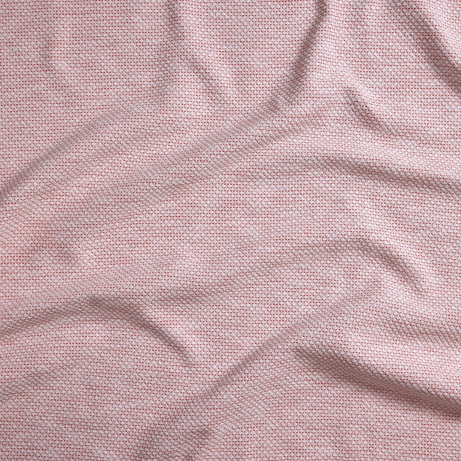 Close up of gently draped woven Indoor-Outdoor fabric with basketweave texture in white and coral red.