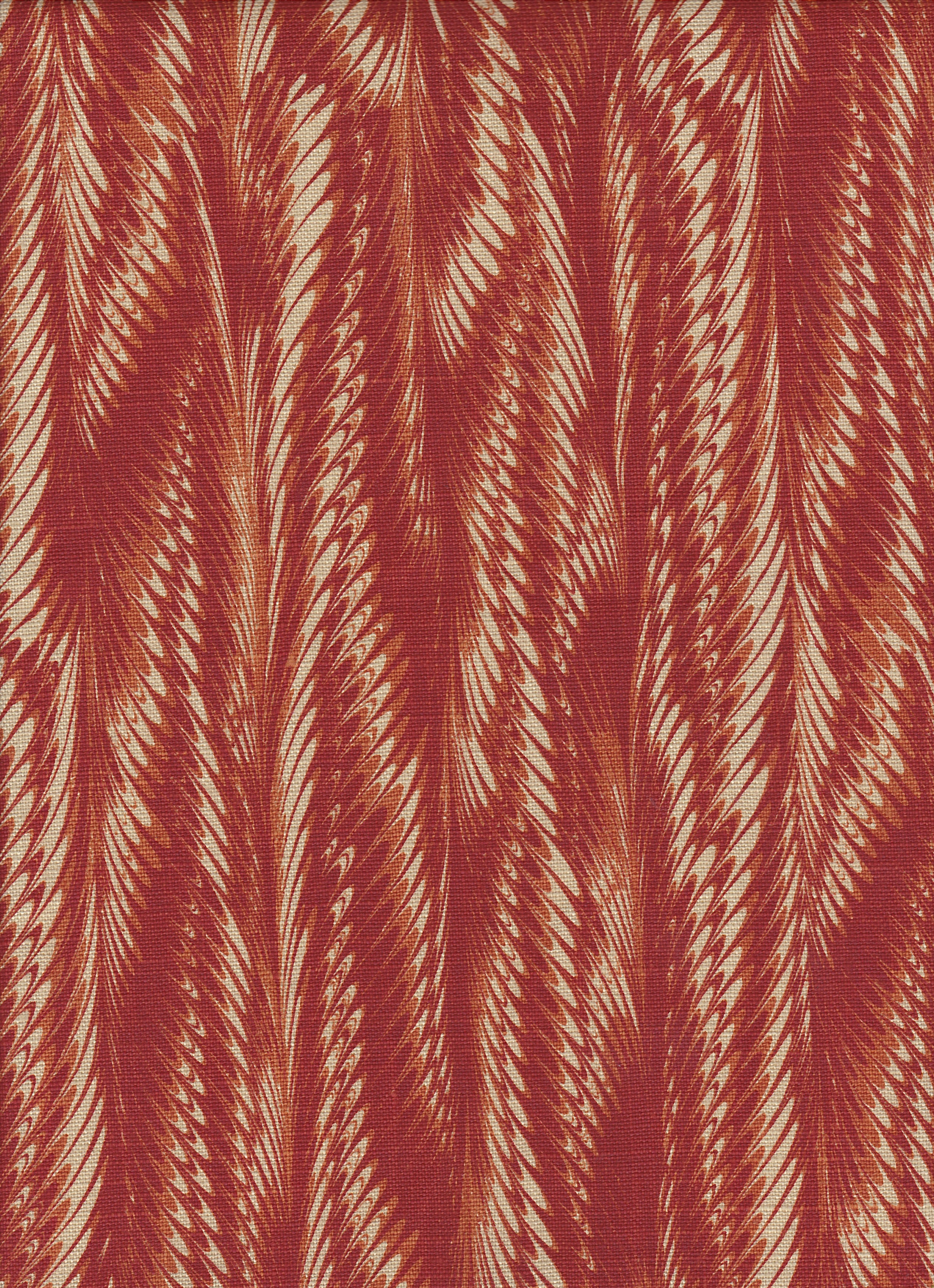 Detail of fabric in a marbled paint print in shades of red, orange and tan.