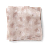 Stacked swatches of fabric in a painterly animal print in pastel pink with white accents. 