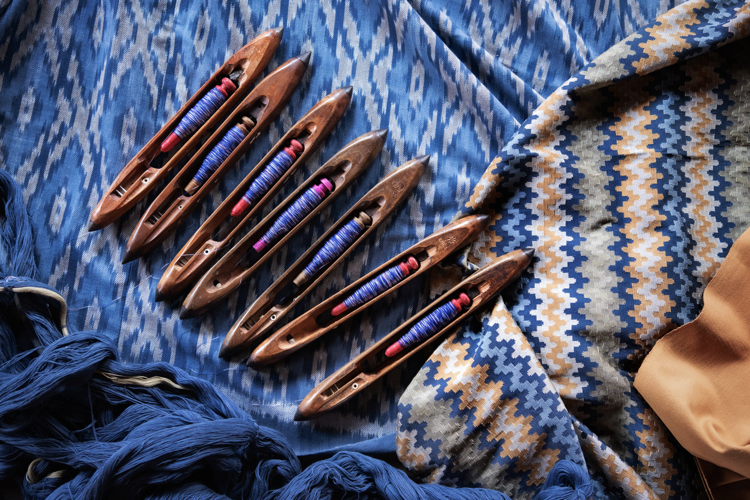 Set of wooden weaving tools with colorful threads on a patterned fabric background