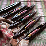 Set of black weaving shuttles with colorful thread on a patterned fabric background