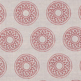 Detail of fabric in a repeating circular geometric print in red on a greige field.