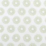 Detail of fabric in a repeating circular geometric print in green on a white field.