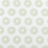 Detail of fabric in a repeating circular geometric print in green on a white field.