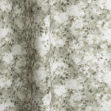 Gently draped fabric in a painterly leaf print in shades of grey-green with a mottled white overlay.