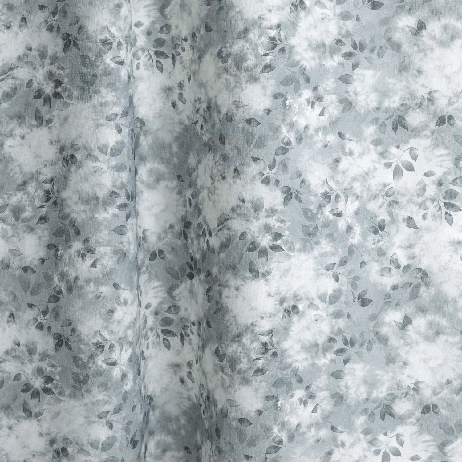 Gently draped fabric in a painterly leaf print in shades of steel blue and teal with a mottled white overlay.