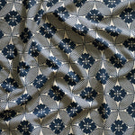 A close-up of gently draped printed linen featuring a Japanese inspired floral lattice design in navy blue on white. 