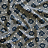 A close-up of gently draped printed linen featuring a Japanese inspired floral lattice design in navy blue on white. 