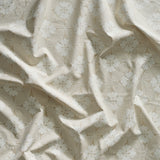A close-up of gently draped printed linen featuring a Japanese inspired floral lattice design in white on ecru.