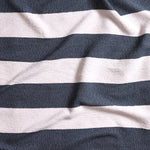 Close up of gently draped woven Indoor-Outdoor fabric with wide textural stripes in white and navy blue.