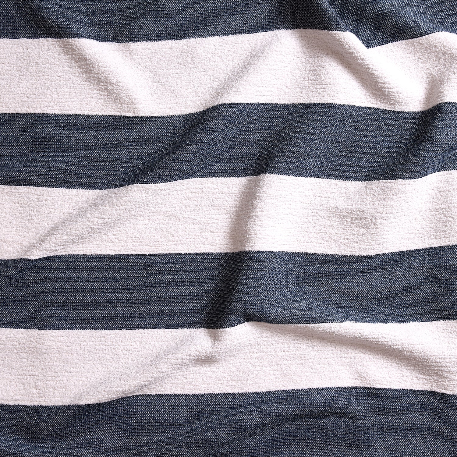 Close up of gently draped woven Indoor-Outdoor fabric with wide textural stripes in white and navy blue.
