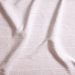 Close up of gently draped woven Indoor-Outdoor fabric with wide textural stripes in white. 