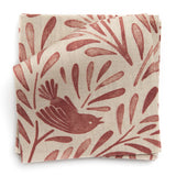 A stack of fabric swatches in a playful bird and leaf print in red on a cream field.