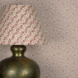 Decorative lamp against wWallpaper in a lyrical wildflower design in cream with rust accents on a lilac field. 