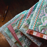 Stack of colorful fabric swatches on a wooden surface