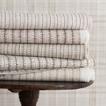 Stack of patterned fabrics on a wooden table with a neutral background