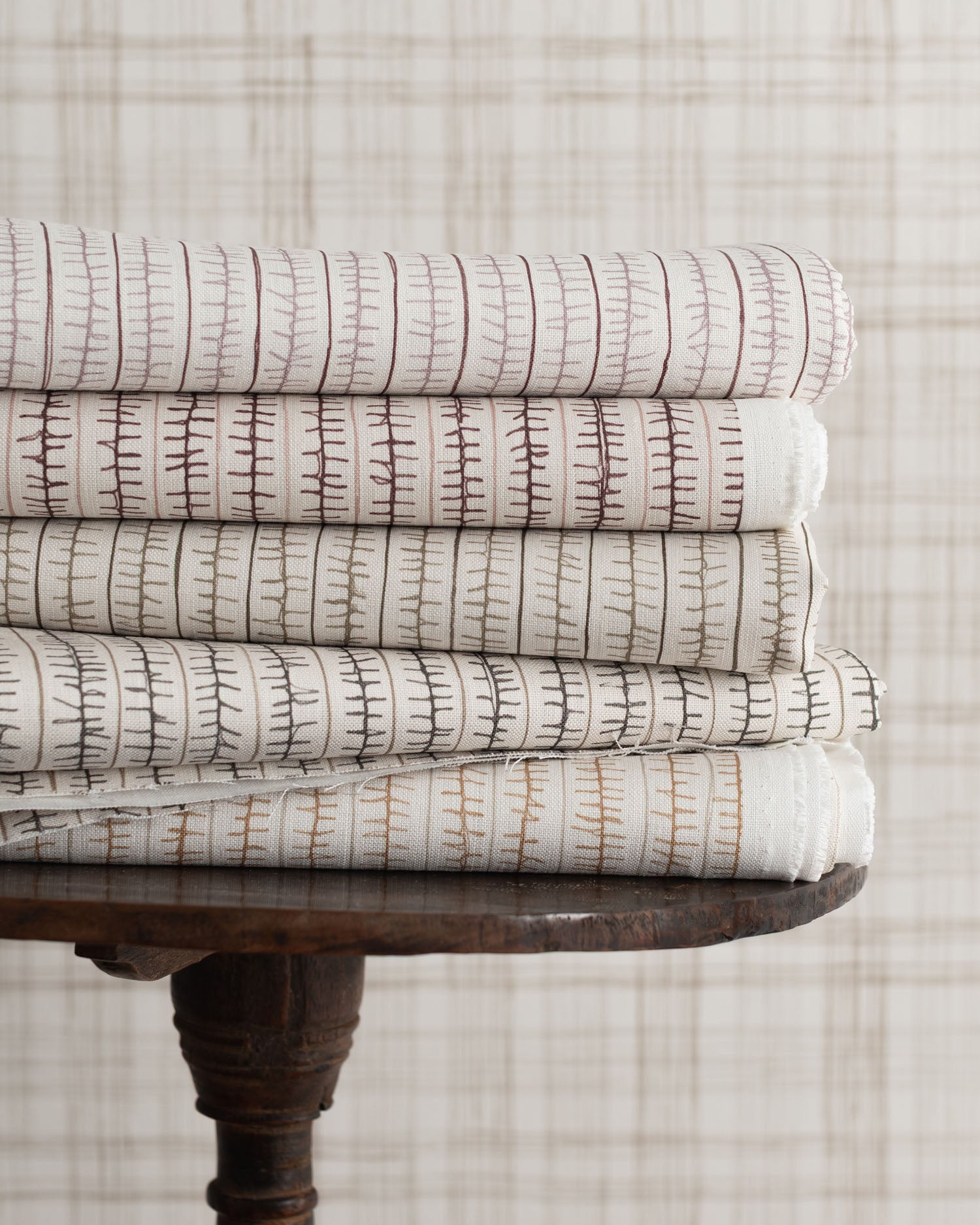 Stack of patterned fabrics on a wooden table with a neutral background