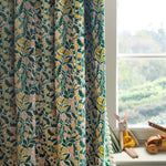 A children's room with a window and curtain in a small-scale floral print in green, yellow and coral on a white field.